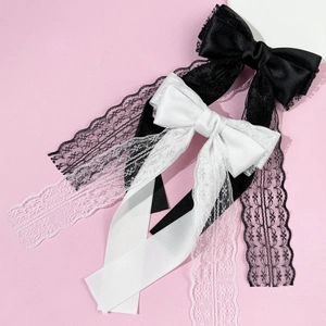 Macro shot of satin and lace bow hair clips with long streaming ribbons in black and white