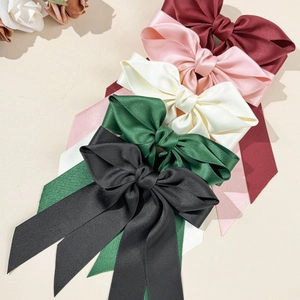 Gros plan de cinq nœuds papillon en satin colorés avec longs rubans et texture soyeuse