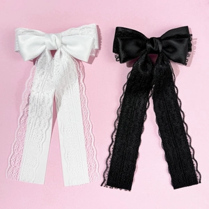 Detail of elegant black and white lace bow hair clips on a soft pink background