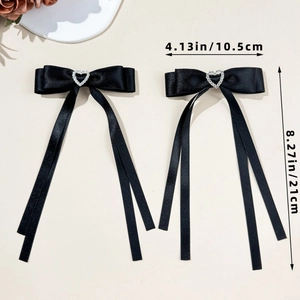 Detail of black satin bow hair clips with heart rhinestones and long ribbons