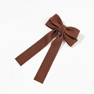Detailed close-up of dark brown velvet bow hair clip with elegant long hanging ribbons