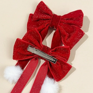 Detailed view of red velvet bow hair clips with gold glitter and white pompom details