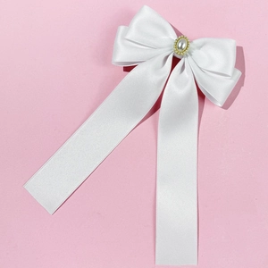 Détail d'une barrette à cheveux nœud en satin blanc avec perle et longs rubans