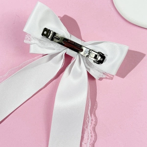 Detail of the silver metal spring clip on white lace and satin bow hair accessory