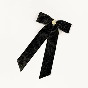 Detail of black glitter velvet bow hair clip with central pearl and rhinestone trim