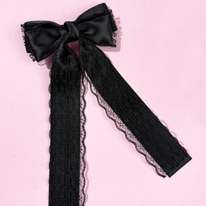 Detail of elegant black lace bow hair clip with textured ribbon on pink background