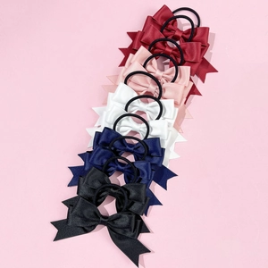 Close-up of colorful satin bow hair ties in red pink and white on pink background