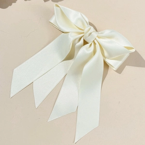 Détail de la pince à cheveux en satin crème avec de longs rubans élégants au style raffiné