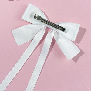 Close-up of white satin ribbon bow hair clip with silver metal alligator grip