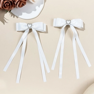 Detail of white silk bow hair clip with heart rhinestone and long elegant ribbon stream