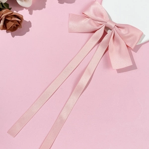 Detailed view of the pink satin bow hair clip with long silk ribbons and pearly texture