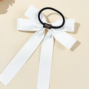 Detail of white satin bow hair tie with handmade label and elastic black band