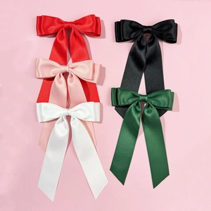 Elegant satin bow hair clips with long ribbons in multiple colors on pink background