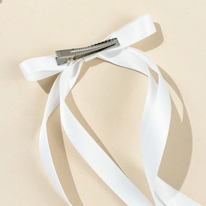 Barrette à nœud en ruban de satin blanc avec un clip crocodile en métal sur fond beige