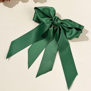 Vue détaillée du nœud en satin vert foncé avec longs rubans élégants sur fond crème épuré
