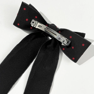 Detailed view of the back silver metal spring clip on a black polka dot bow hair clip