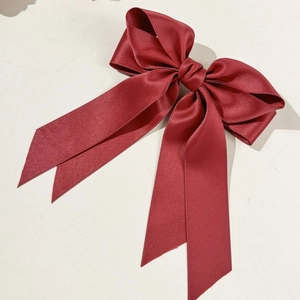 Gros plan détaillé d'une pince à cheveux à double nœud en satin bordeaux avec rubans