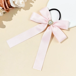 Elegant pink satin bow hair tie with a heart-shaped pearl center and rhinestone details
