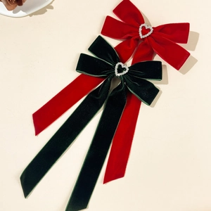 Close-up of velvet ribbon hair bows with rhinestone heart charms in red and green colors