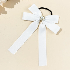 Detail of white ribbon bow hair scrunchie with heart pearl and rhinestone decor