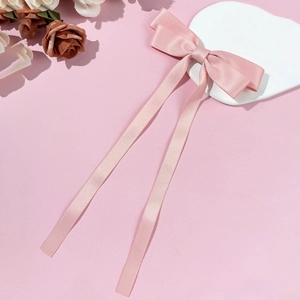 Dettaglio del fermaglio per capelli con fiocco in raso rosa e lunghi nastri eleganti