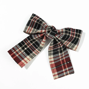 Close-up of British plaid bow hair clip with sparkling rhinestones and textile texture