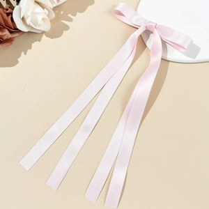 Détail d'un nœud en satin rose clair avec de longs rubans sur fond crème doux