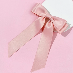Detailed macro view of the pink satin ribbon hair clip with high-density fabric texture