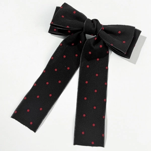 Detail of a large black hair clip with red polka dots and long elegant ribbons