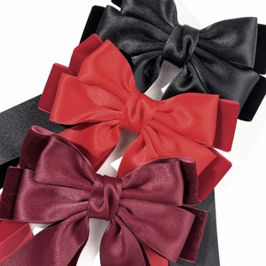 Detail of layered satin and velvet bow hair clips in black, red, and burgundy colors