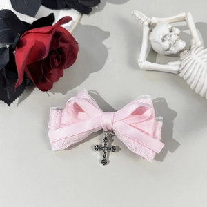 Detalle de lazo de encaje rosa con colgante de cruz plateada de estilo gótico
