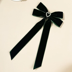 Detailed macro view of dark green velvet bow hairpin with heart diamond buckle