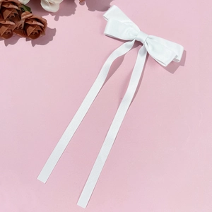 Dettaglio del fiocco per capelli in raso bianco con nastri lunghi su sfondo rosa