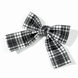 Close-up of black and white plaid bow hair clip with subtle silver sequins on fabric