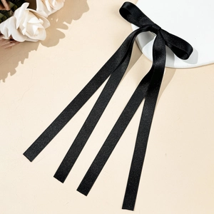 Détail d'un nœud en ruban gros-grain noir avec de longs pans sur fond élégant beige