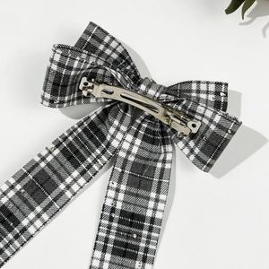 Detail of checkered bow hair clip with sequins and silver metal spring fastener