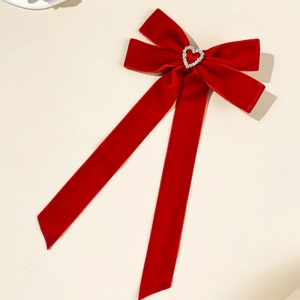Detailed macro view of deep red velvet bow with heart-shaped rhinestone and long streamers