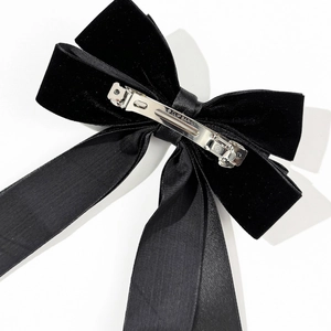 Close-up of black velvet bow hair clip back with engraved silver spring metal fastener