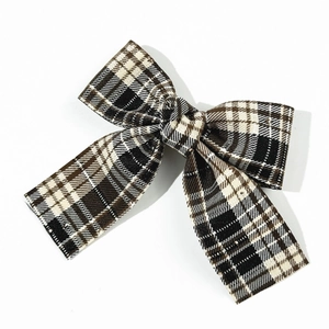 Detailed close-up of British style plaid bow hair clip with vintage brown and black patterns