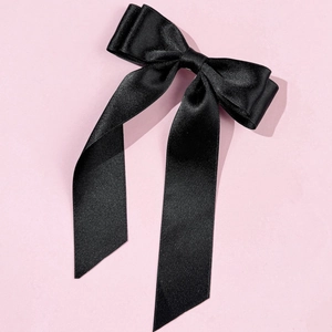 Detailed view of elegant black satin double bow hairclip with long hanging ribbons