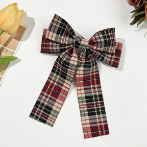Detailed view of British style red plaid bow hair clip with long ribbons and sequins