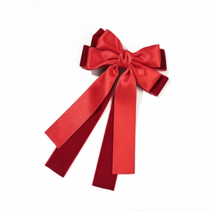 Detail showing red satin and velvet double layered bow hair clip with long ribbons