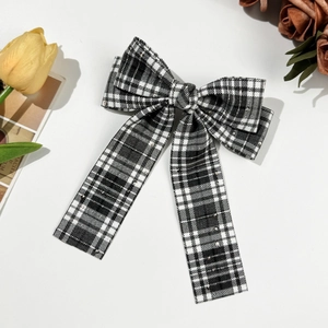 Detail view of a plaid bow hair clip with sparkling rhinestones and ribbon tails