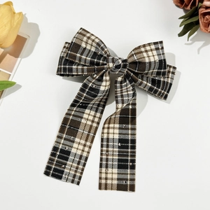 Detail of a vintage plaid bow hair clip with sequins and streamers on a white background