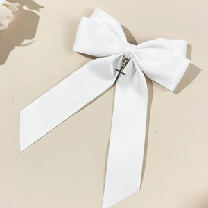 Gros plan sur un nœud en satin blanc orné d'un pendentif en forme de croix en argent