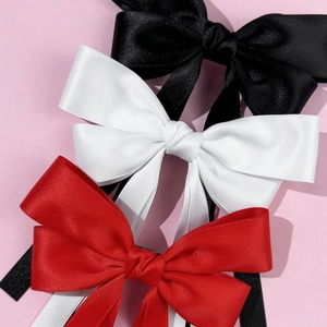 Elegant satin bow hair clips in black, white, and red with a silky ribbon texture