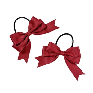 Pair of deep red silk bow hair ties with elastic bands on a white background
