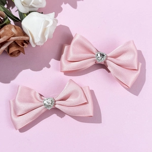 Detailansicht von rosa Satin-Haarschleifen mit herzförmigem Strassstein im Set aus zwei Teilen