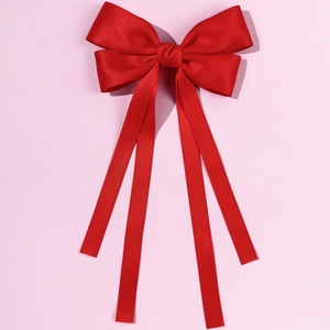 Elegant large red satin bow hair clip with long ribbons on a soft purple background