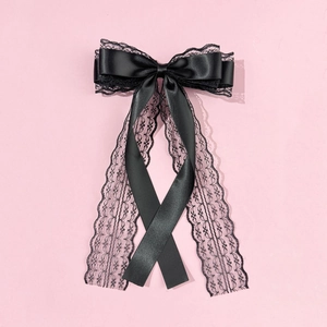 Detailed view of black lace and satin layered bow hair clip with long elegant streamers
